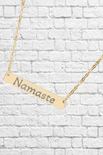 Load image into Gallery viewer, Gold necklace with 'Namaste' pendant on a white brick wall background
