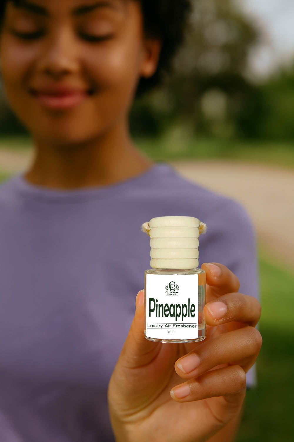 Person holding a small bottle labeled 'Pineapple' outdoors