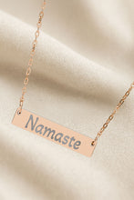 Load image into Gallery viewer, Necklace with 'Namaste' pendant on a beige fabric background
